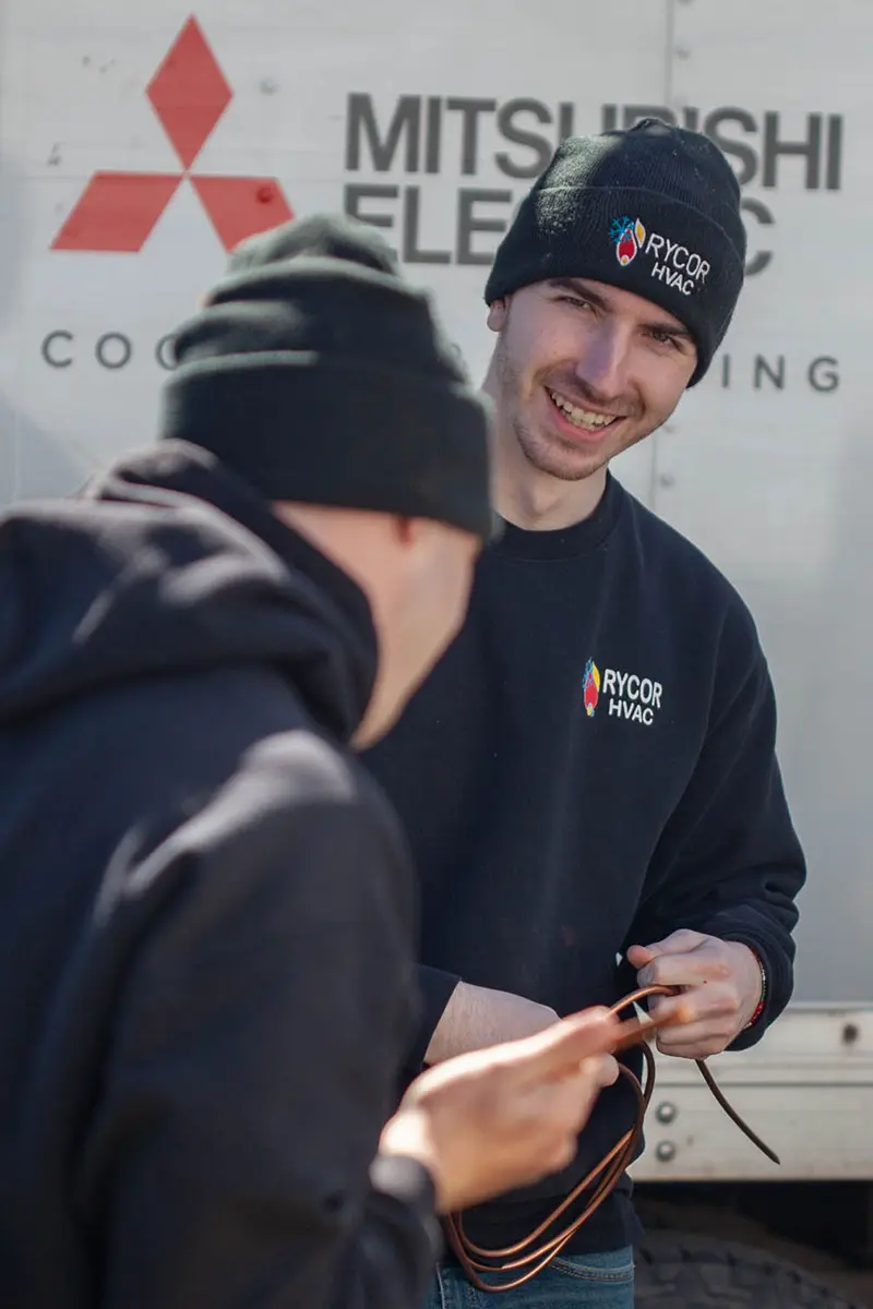 Two young installers in front of a truck smiling.