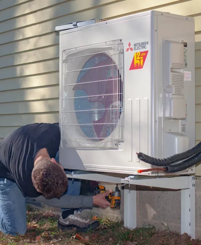 Technician under a heat pump unit installing to house