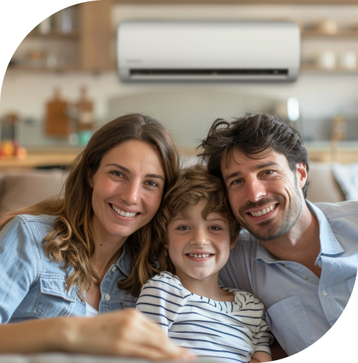 A family smiling and sitting on their couch while being comforted by a ductless mini-split system installed in the kitchen